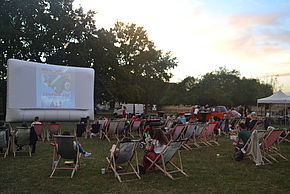 Photo du ciné plein air 2022 avec le public assis dans des transats devant un écran de cinéma dans le parc du Château Soubiran - Agrandir l'image